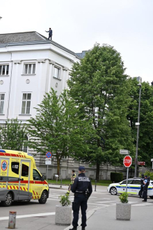 Na robu strehe parlamenta stoji moški, poteka policijska intervencija