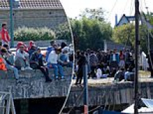 The queue for Dover? Pictures show large group of men idling by notorious French people smuggling port as UK little boat arrivals pass 50,000 since Labour swept to power last year 