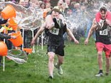 Couples take part in the UK's wife-carrying race as husbands haul their partners around 1,200ft course on International Women's Day