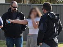 Teen girl wearing tracksuit pants and clutching a vape is dragged out of her home and arrested over alleged role in underworld 'surveillance operation'