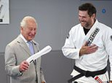 Jiu Jitsu King! Charles is given a white belt - and some plastic overshoes - during heatwave visit to London martial arts charity