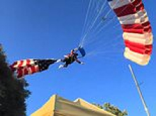 Patriotic skydiver flying huge American flag gets caught in tree and CRASHES into horrified rodeo crowd