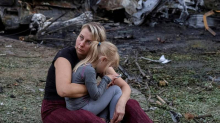 FOTO UŽASA Majka drži dijete, u pozadini sve izgorjelo.  Novi stravičan napad Rusa na Kijev