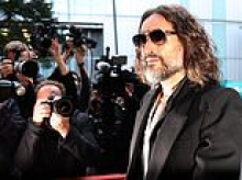 JAN MOIR: A disciple tweaked the defendant's white scarf and fluffed his curls... Russell Brand was ready for his close-up