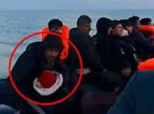 Moment small boat migrant holds baby in his arms as he pilots overcrowded dinghy across the Channel